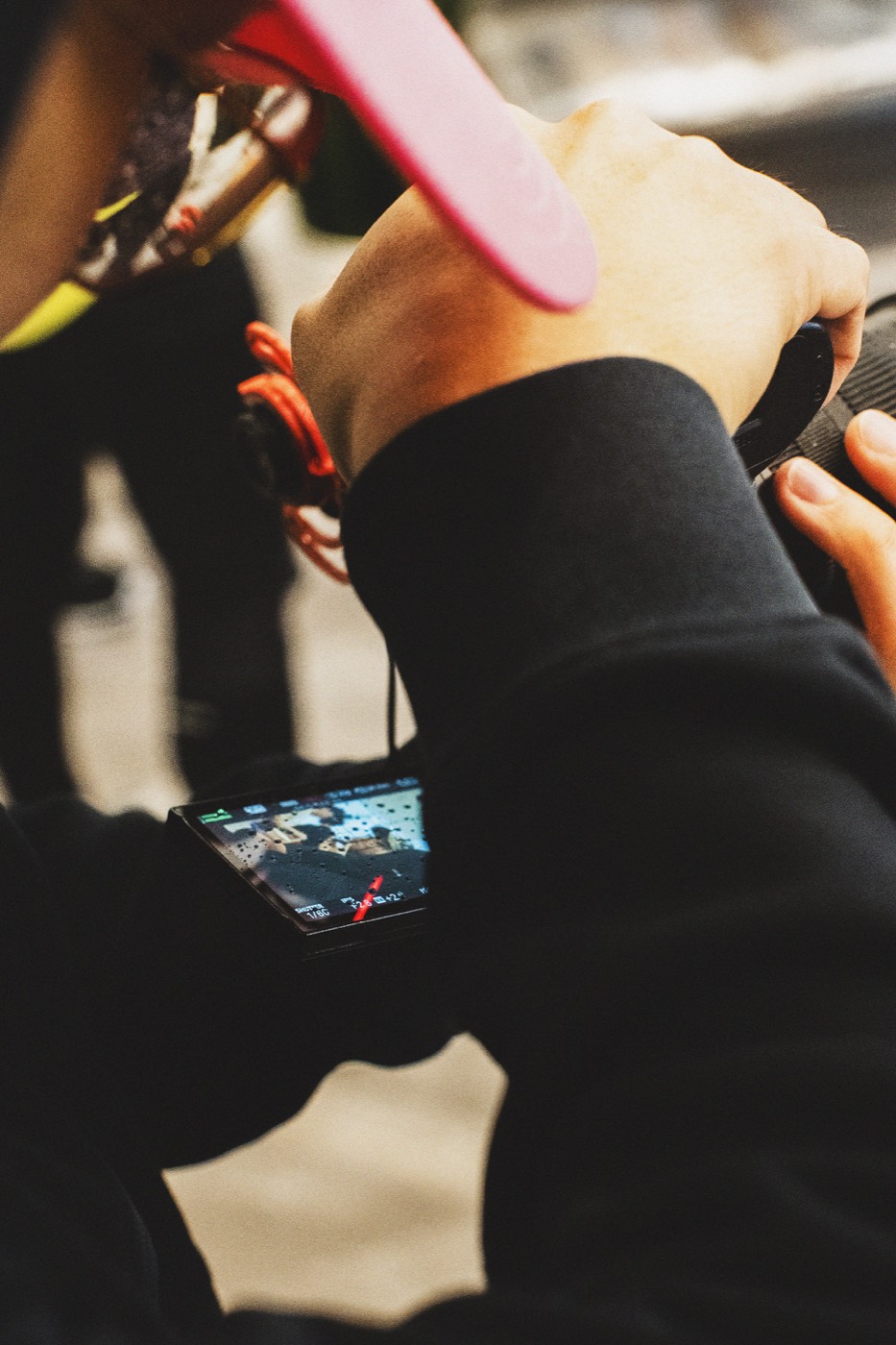 Close-up of hands holding a camera monitor while filming
